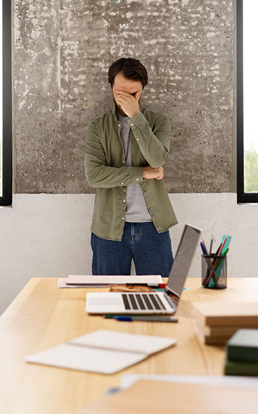 Gestresster Mann im Büro, der die negative Arbeitsatmosphäre erlebt. Ursachen und Lösungen für ein gesundes Arbeitsklima in der Hörakustik-Praxis auf audimus.eu.