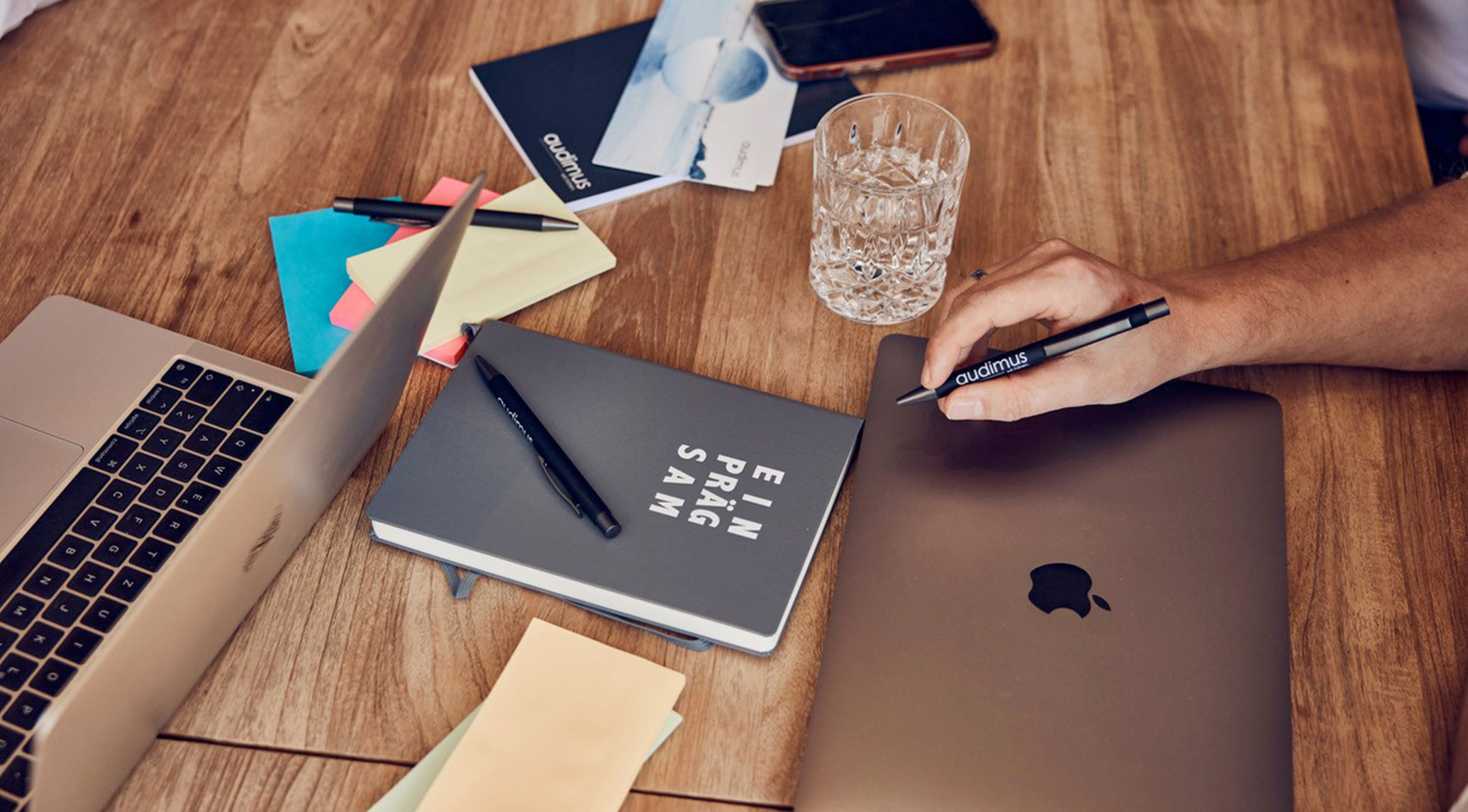 Remote-Arbeit in der Hörakustik: Arbeitsplatz mit Laptop, Notizbuch und Audimus-Stift zur Verwaltung von Hörakustik-Projekten.